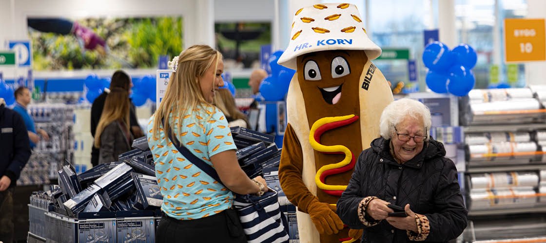 Biltemas fasad i glas och vitt med tydlig skyltning av öppettider och café. 