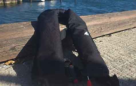 En uppblåsbar flytväst ligger ihoppackad på bryggan.