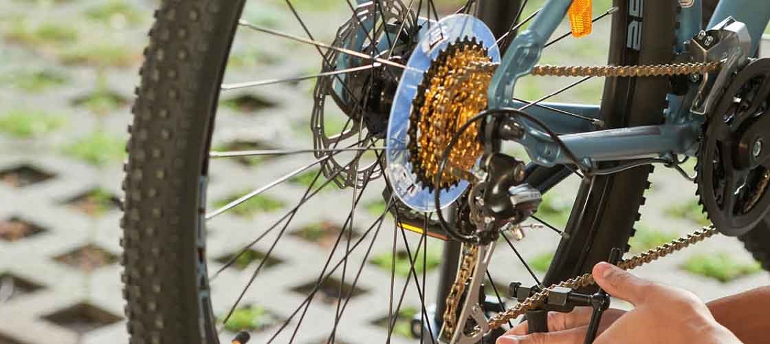 Närbild på en hand som justerar en cykelkedja i utomhusmiljö.