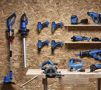 Trädgårdsredskap och maskiner upphängda organiserat på en vägg i ett förråd.