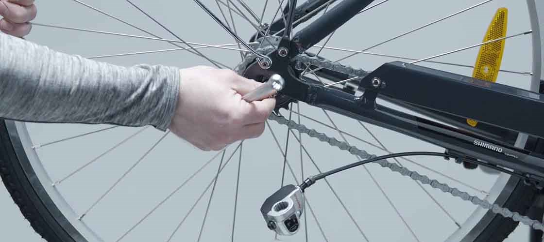 Närbild på en hand som demonterar ett cykelhjul.