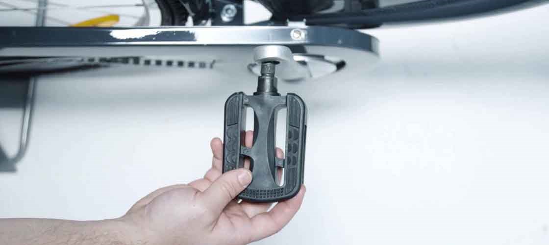 Närbild på en hand som justerar pedalen på en cykel.